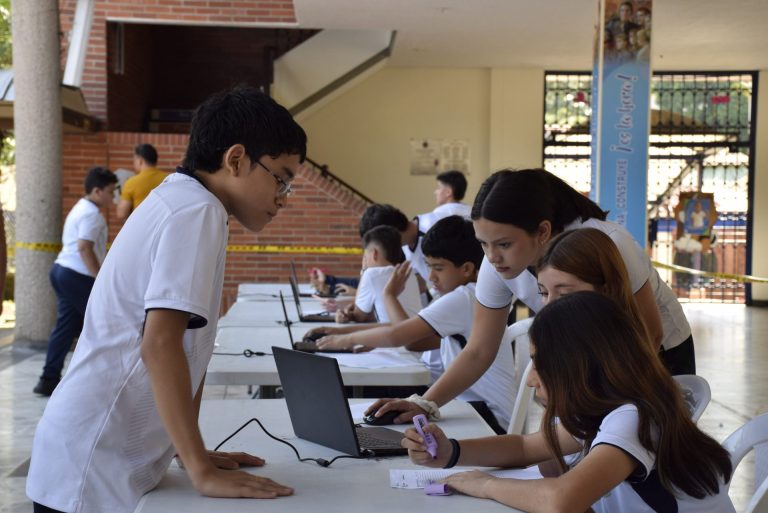 Estudiantes trabajan con portátiles en las mesas de un espacio del colegio.